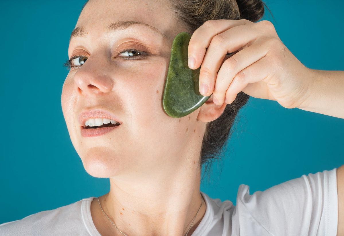 Woman holding a jade face massager to her cheek
